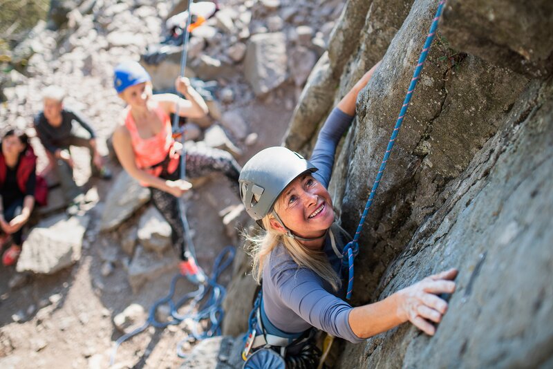 Donna durante un'arrampicata con imbracatura e caschetto